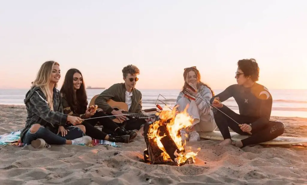 a great reason to travel is hanging with a group of friends on the beach playing a guitar and roasting weiners over a bonfire. happytogetheranywhere.com