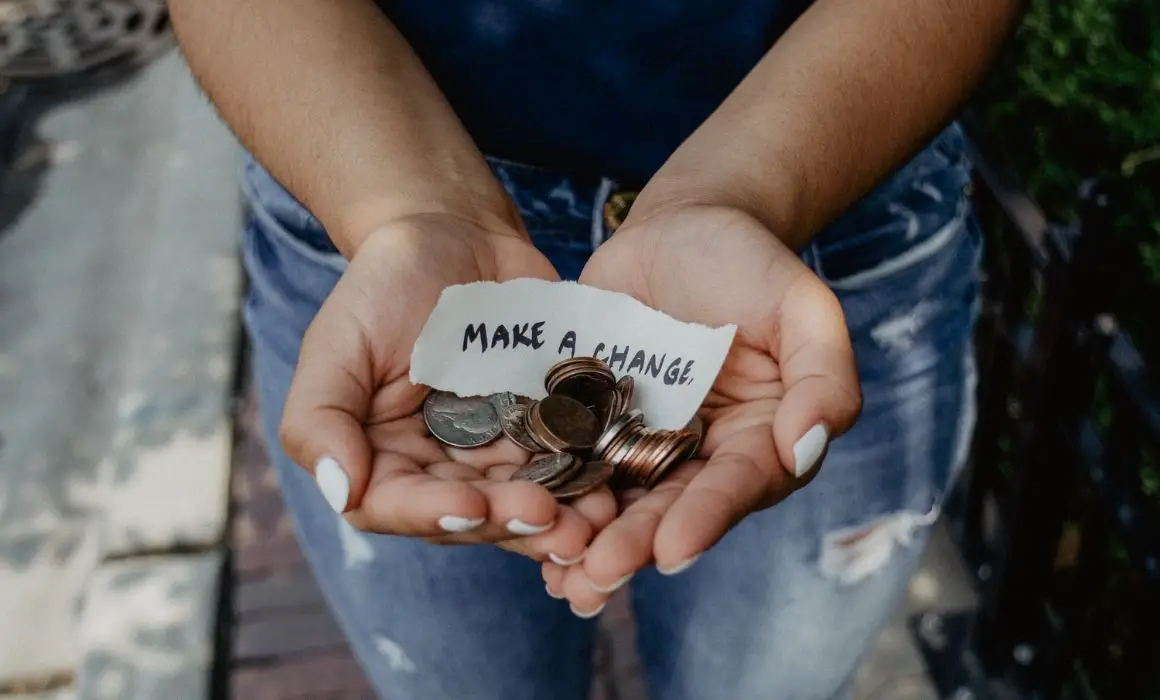 bringing consciousness to finances photo of a woman's hands holding coins and a paper saying make a change