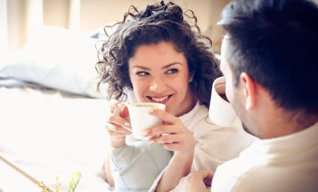 couple drinking coffee and smiling at each other. happytogetheranywhere.com