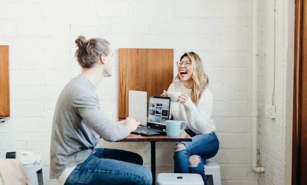 couple planning their conscious relationship on computers laughing. happytogetheranywhere.com