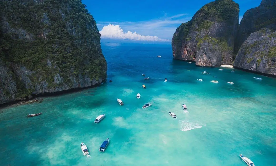many longtail boats in beautiful aqua waters near islands in thailand